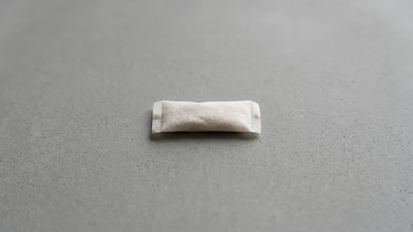 A person holding a nicotine pouch between their fingers.